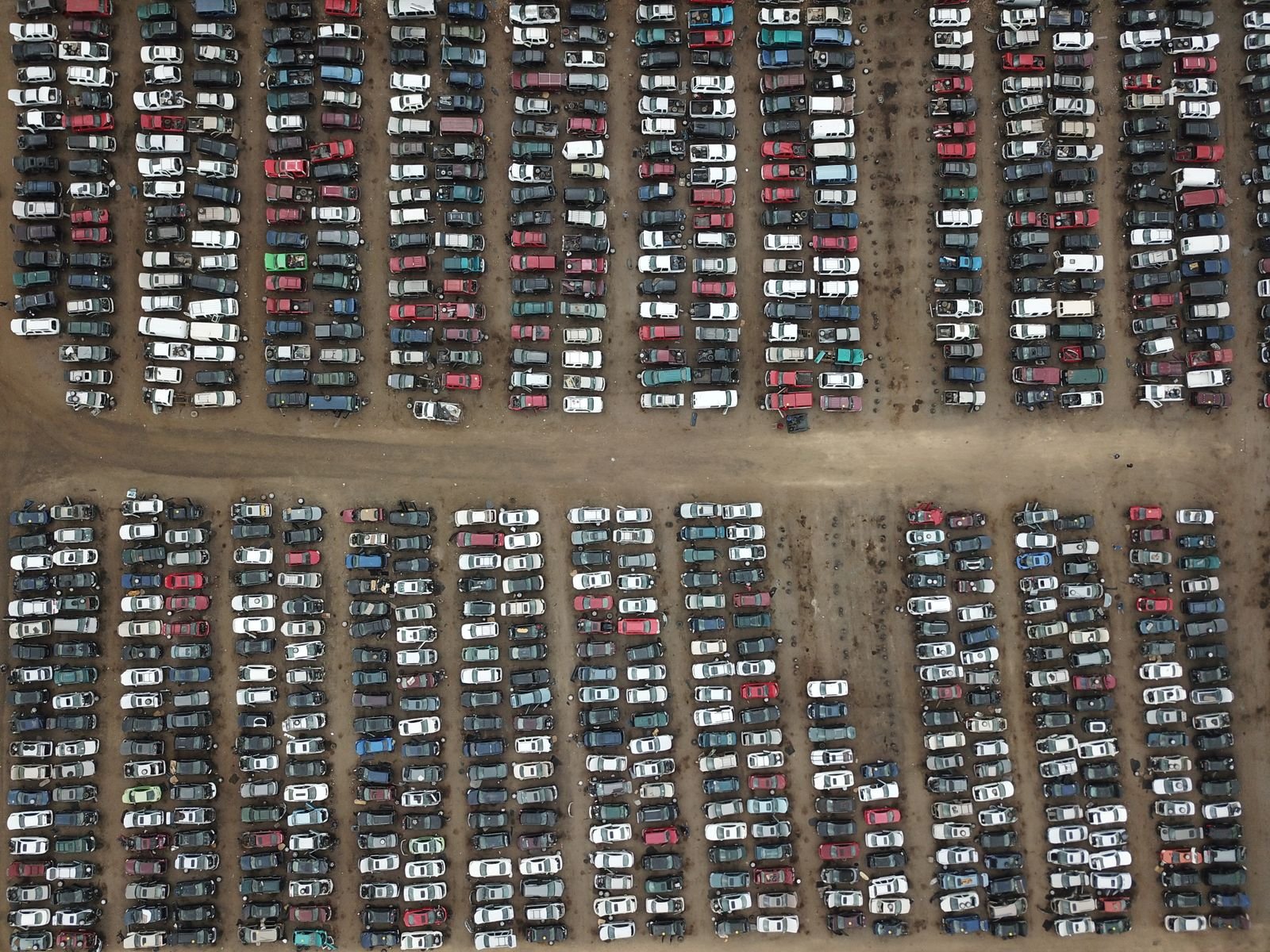 Vista aérea de um pátio com fileiras de veículos estacionados