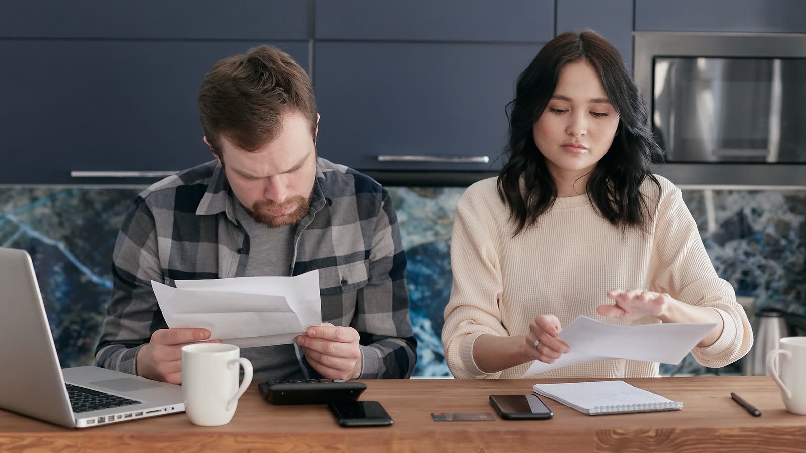 Casal analisa contas e boletos à mesa da cozinha