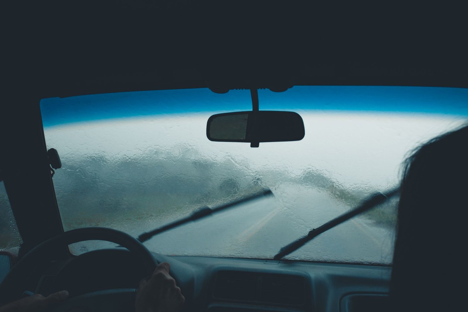 Vista de dentro de um carro com limpadores de para-brisa em funcionamento durante chuva forte na estrada