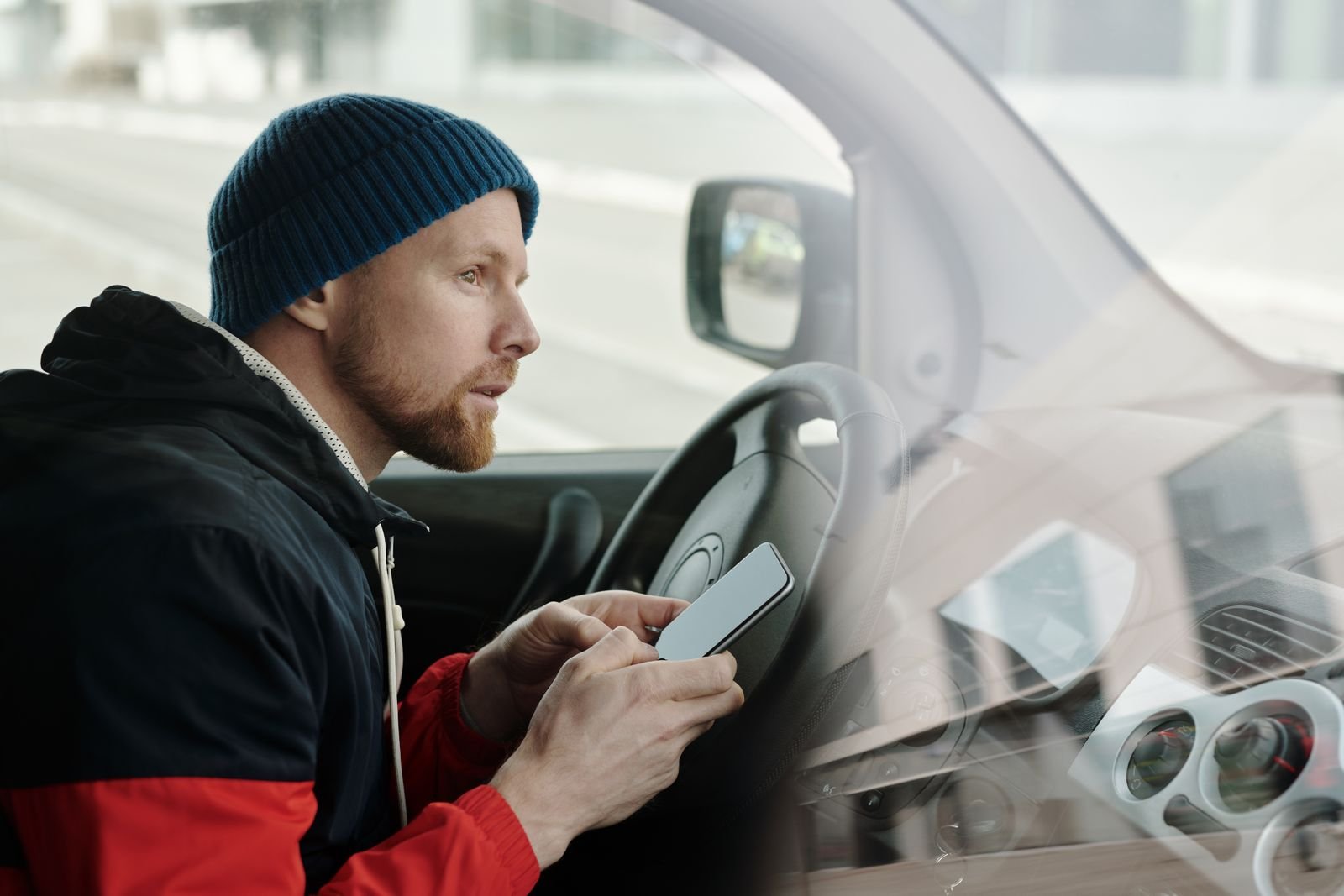 Motorista dentro de um carro segura um celular com a tela apagada, ao volante