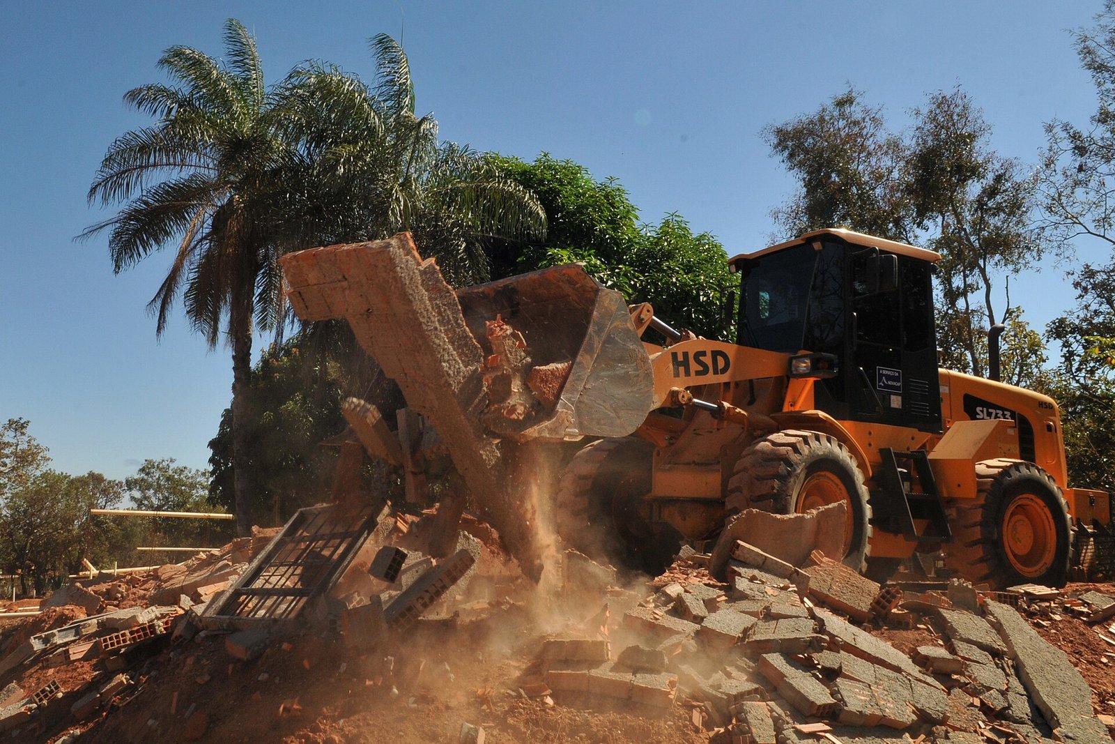 Pá carregadeira derruba construção irregular durante ação de desocupação de área pública no Distrito Federal, em 2016