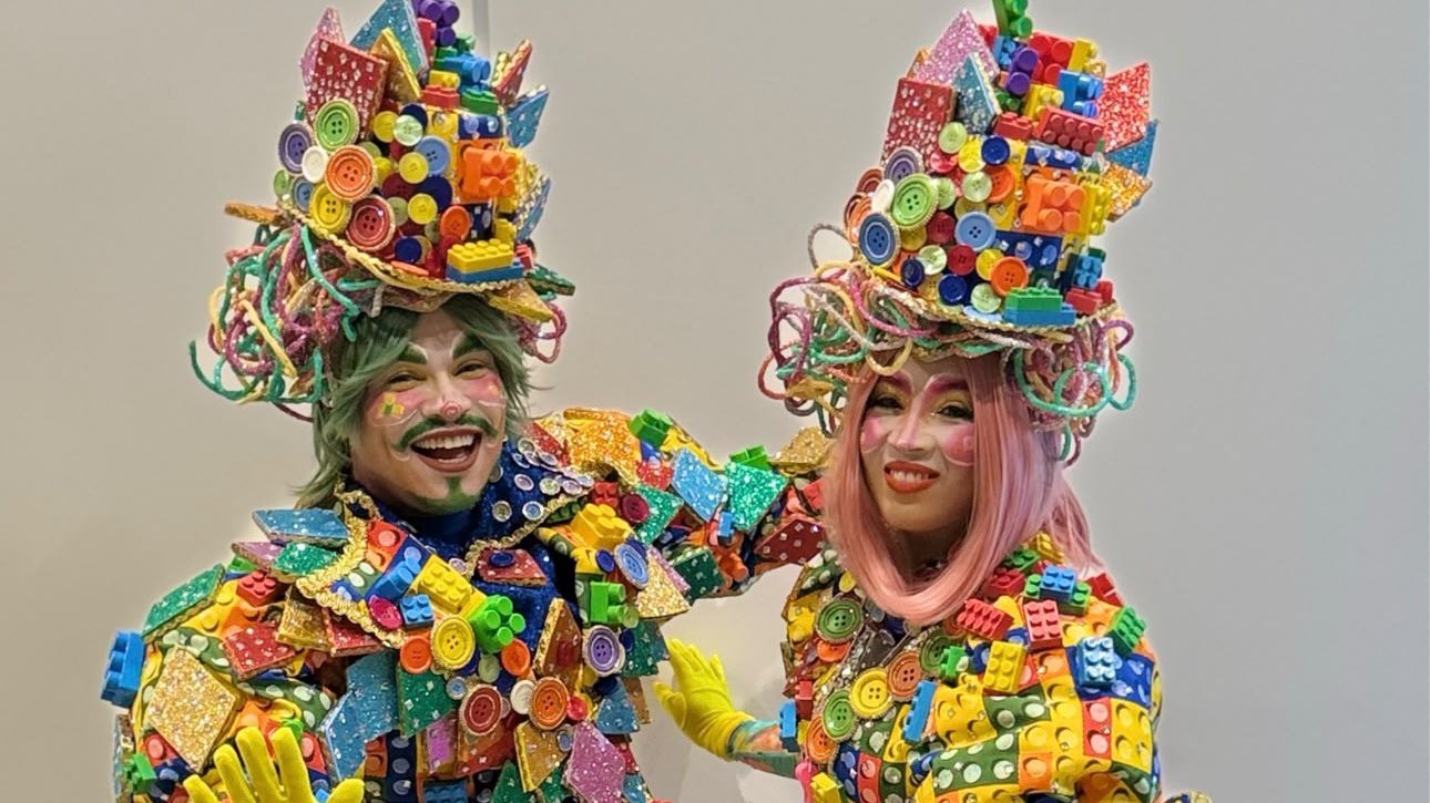 Dois artistas fantasiados com roupas e chapéus coloridos na divulgação do Dia das Crianças do Pontão do Lago Sul