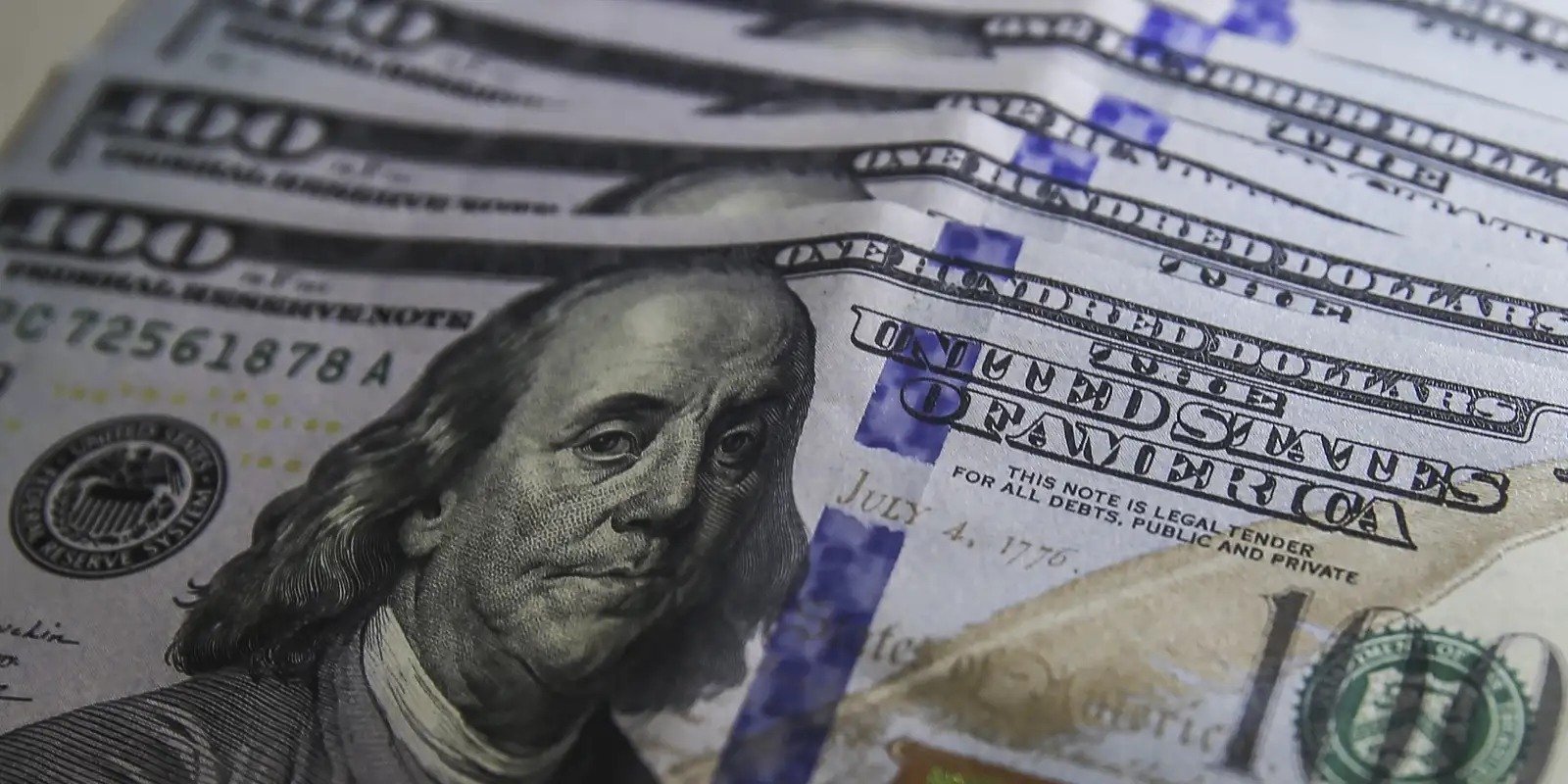 Notas de 100 dólares americanos empilhadas, em close