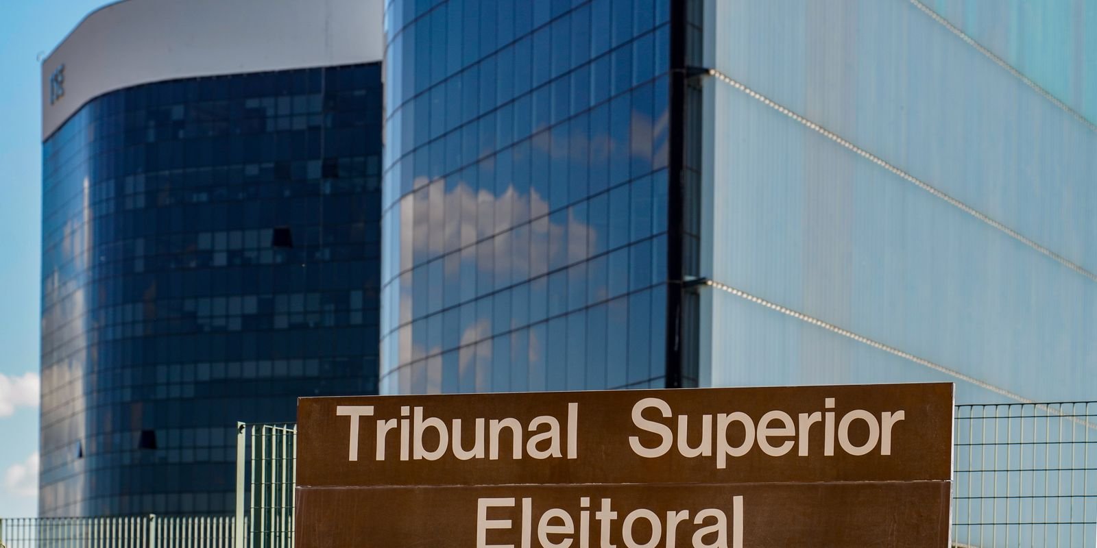 Placa do Tribunal Superior Eleitoral em frente aos prédios de vidro da sede, em Brasília