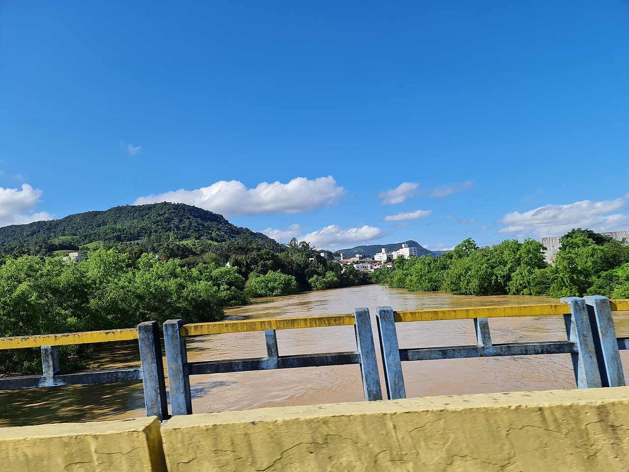 Rio cheio e barrento sob uma ponte em Rio do Sul (SC), durante a enchente de outubro de 2023 (foto de arquivo)