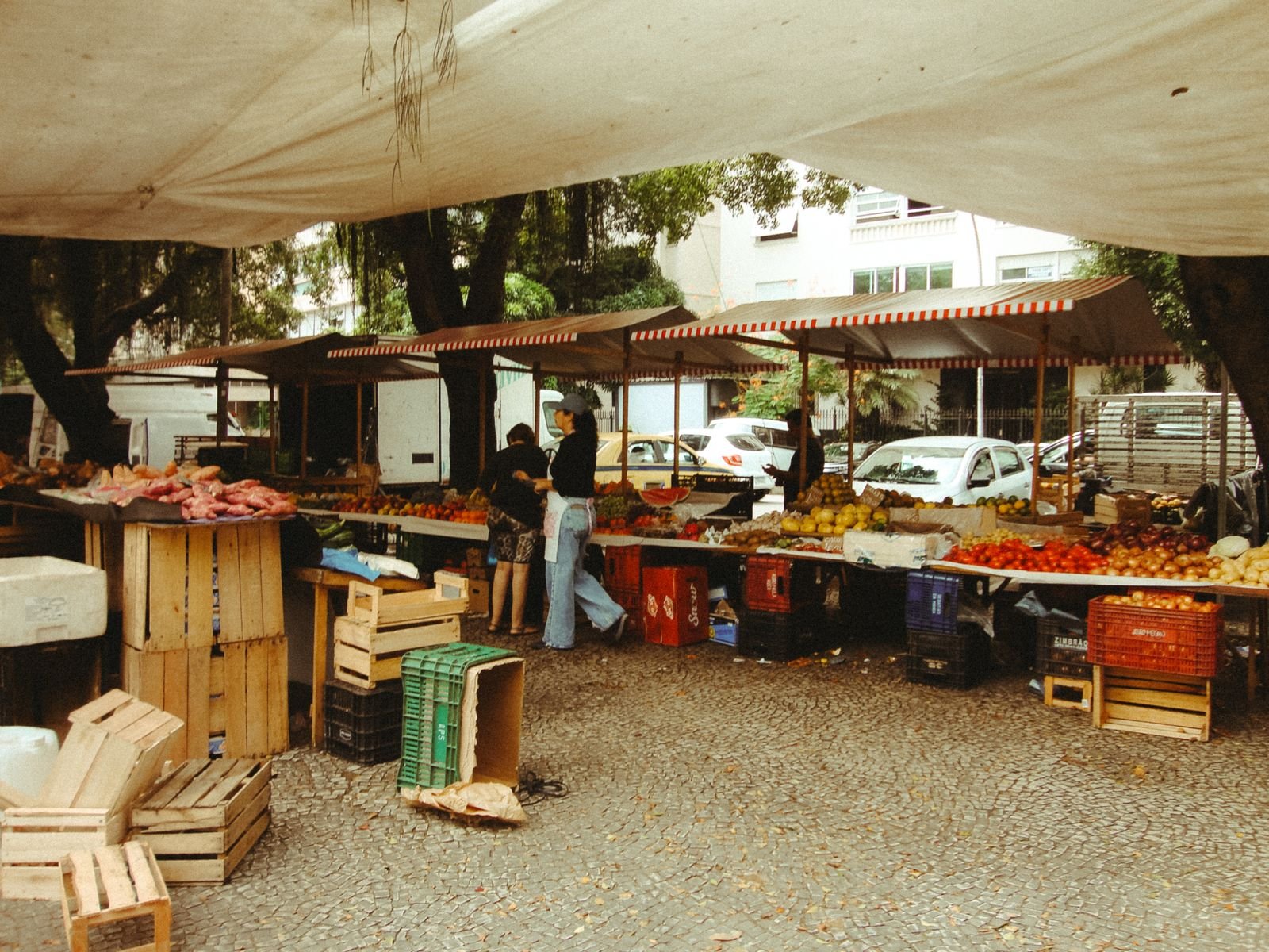 Feira de rua com bancas de frutas e legumes sob toldos, imagem ilustrativa do comércio de bairro