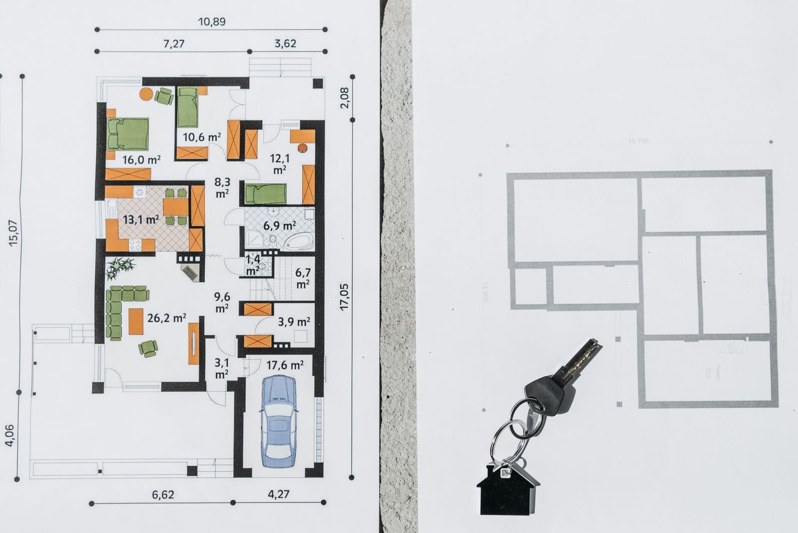 Chave com chaveiro em formato de casa sobre plantas baixas de uma residência (foto ilustrativa)