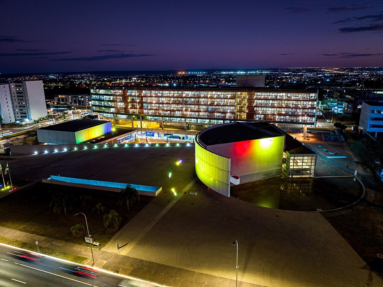 Vista aérea noturna do edifício-sede da Câmara Legislativa do Distrito Federal, com iluminação colorida na fachada
