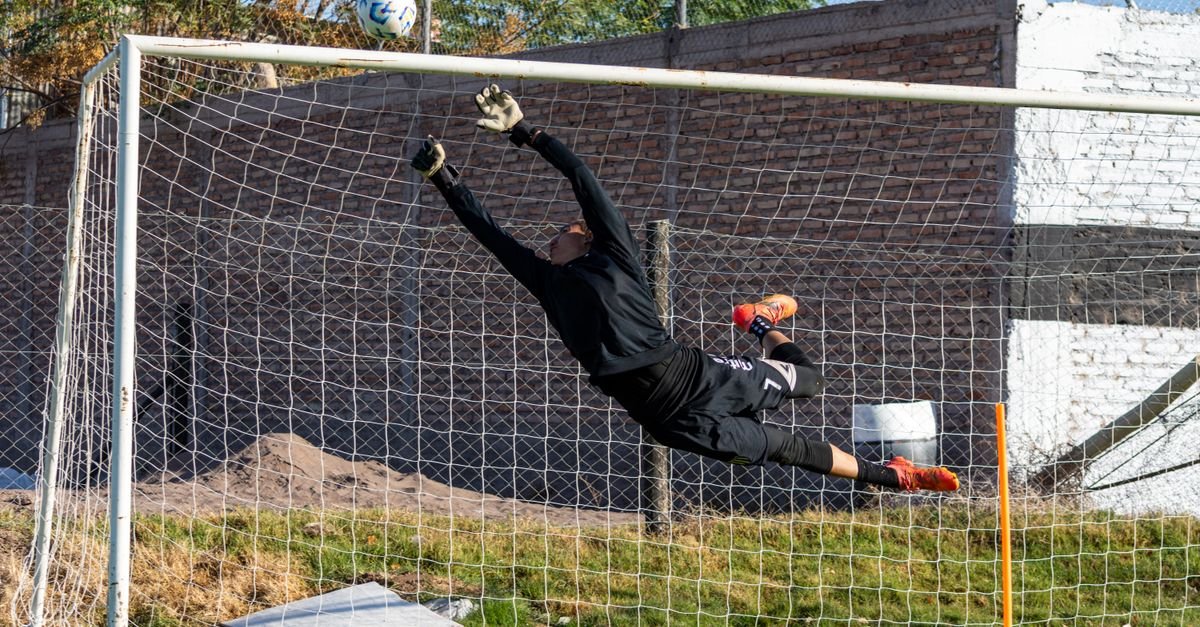 Goleiro em salto para defender chute no gol