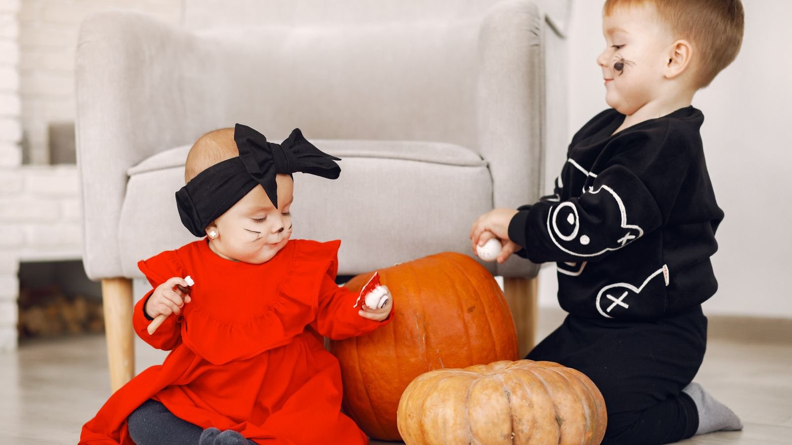 Crianças fantasiadas pintando abóbora de Halloween