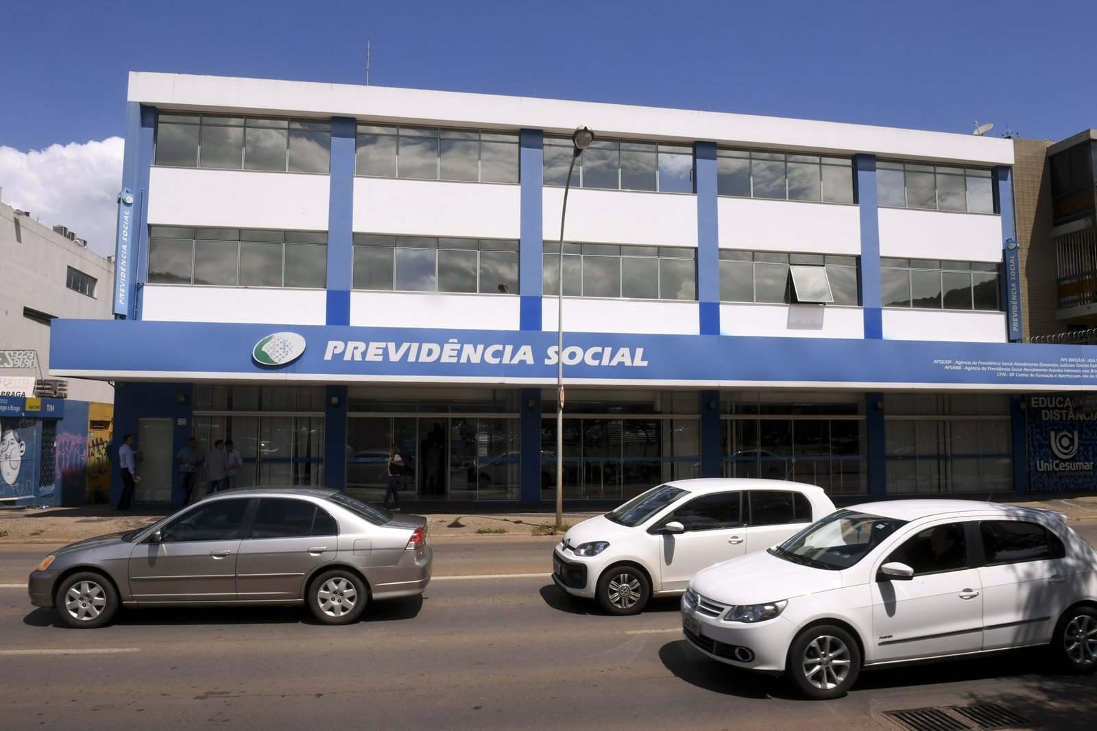 Fachada de agência da Previdência Social em Brasília, com carros passando na rua em frente
