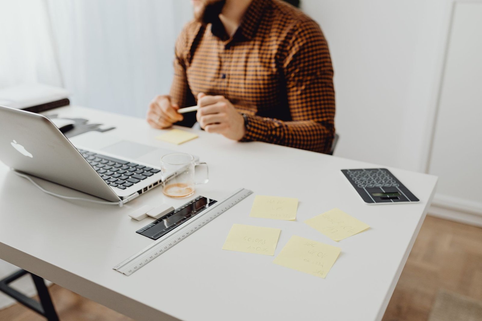 Mesa com notebook, calculadora e notas adesivas de quem cuida da papelada de uma empresa