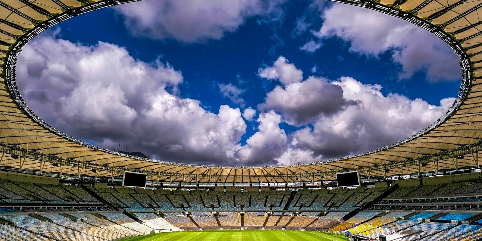 Vista interna do Maracanã, com a cobertura aberta ao céu e as arquibancadas vazias