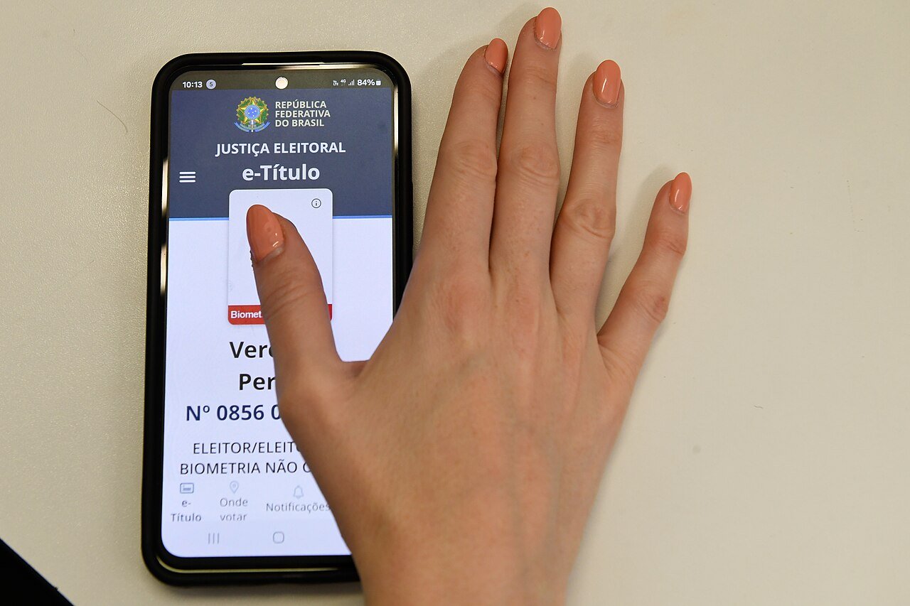 Mão toca a tela do aplicativo e-Título da Justiça Eleitoral em um celular (foto de arquivo)