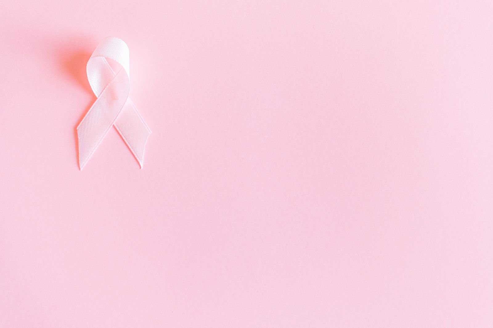 Laço rosa de fita sobre fundo rosa, símbolo do Outubro Rosa; foto ilustrativa