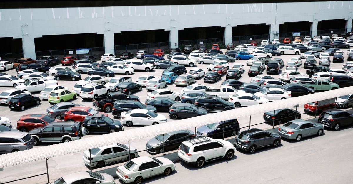 Pátio com dezenas de carros estacionados lado a lado visto do alto
