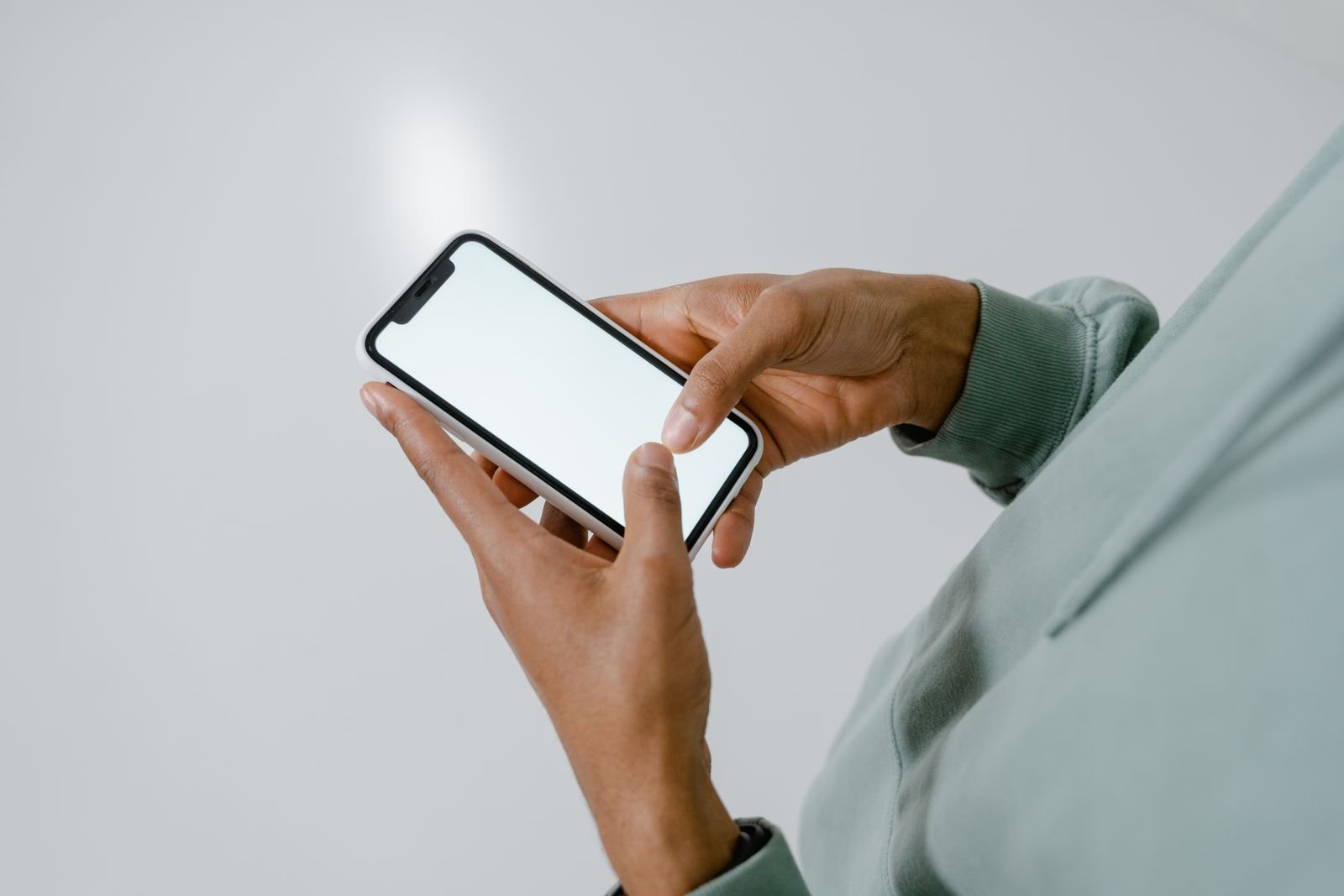 Mãos seguram um celular com a tela clara, em foto de apoio sobre alerta de golpe por mensagem