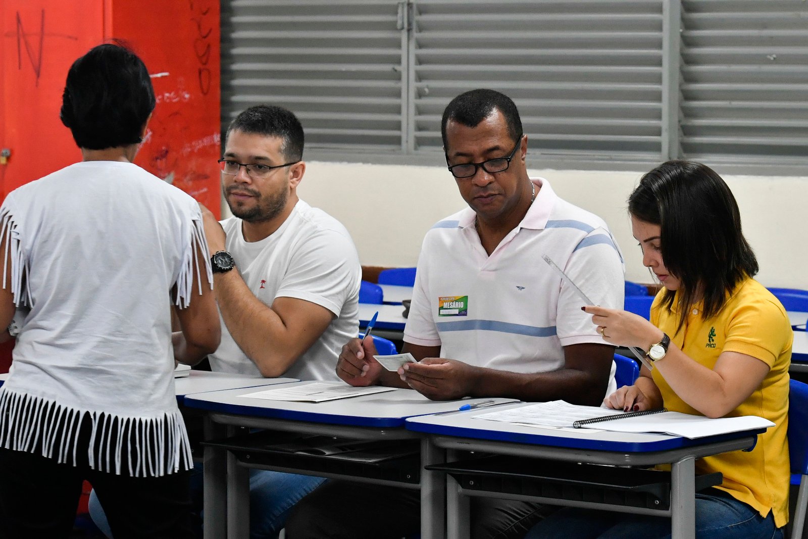 Mesários conferem o título de uma eleitora em seção eleitoral no primeiro turno de 2018, foto de arquivo