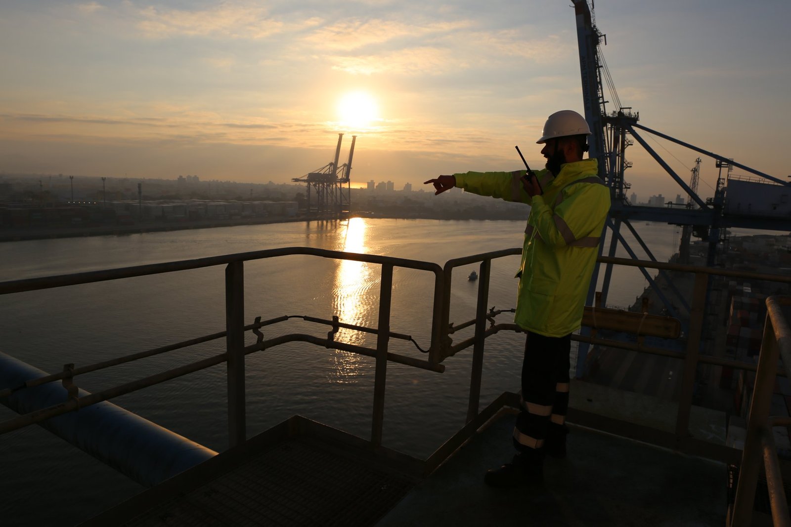 Trabalhador de colete e capacete observa guindastes do porto de Itajaí (SC) ao nascer do sol, em foto de arquivo de 2021
