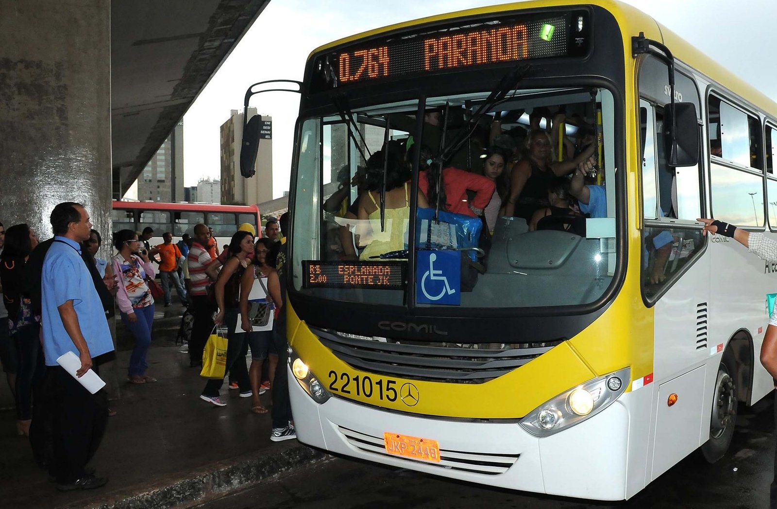 Ônibus amarelo e branco em plataforma da Rodoviária do Plano Piloto, com passageiros em fila