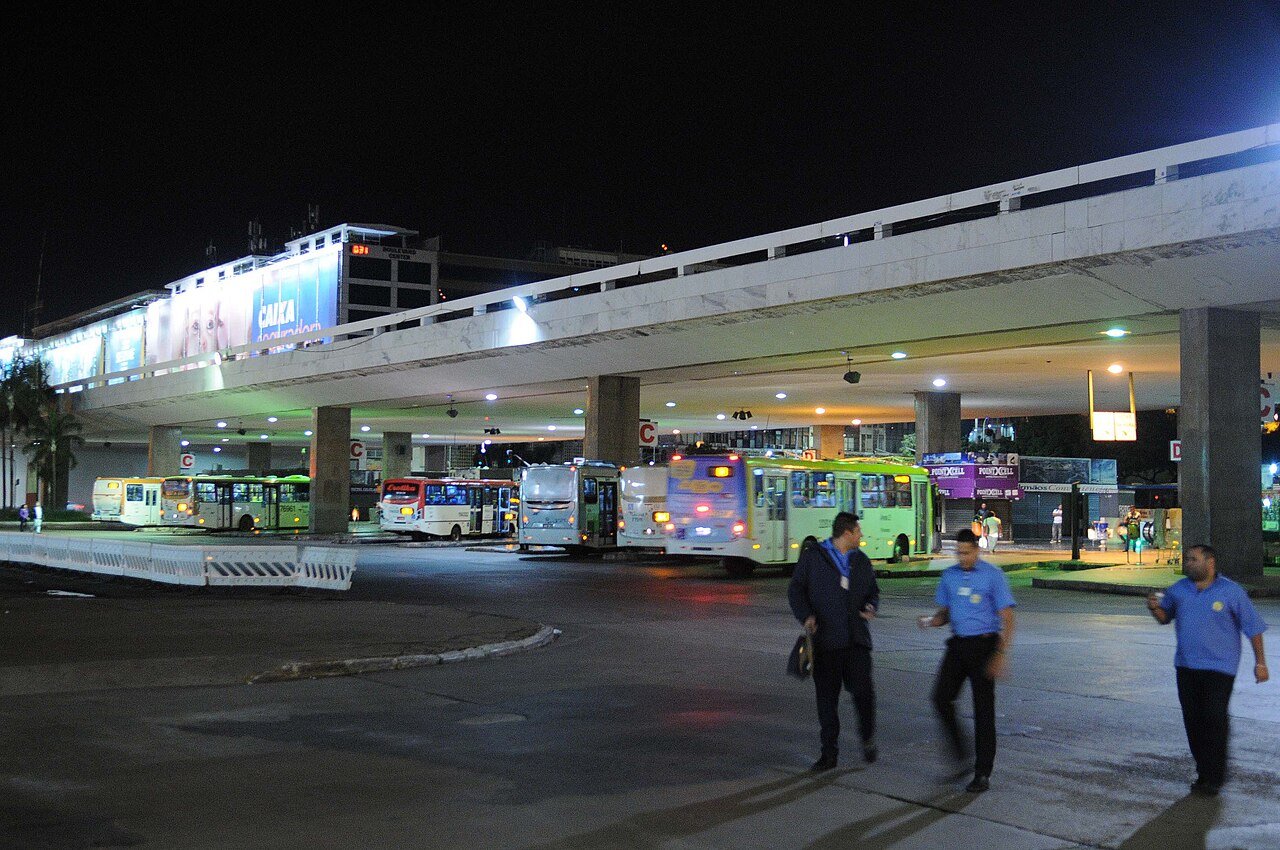 Ônibus estacionados sob a plataforma superior da Rodoviária do Plano Piloto, à noite, com funcionários andando em primeiro plano (foto de arquivo)