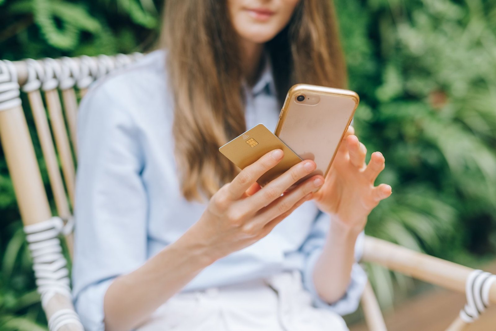 Mulher segura um cartão bancário e um celular; imagem ilustrativa