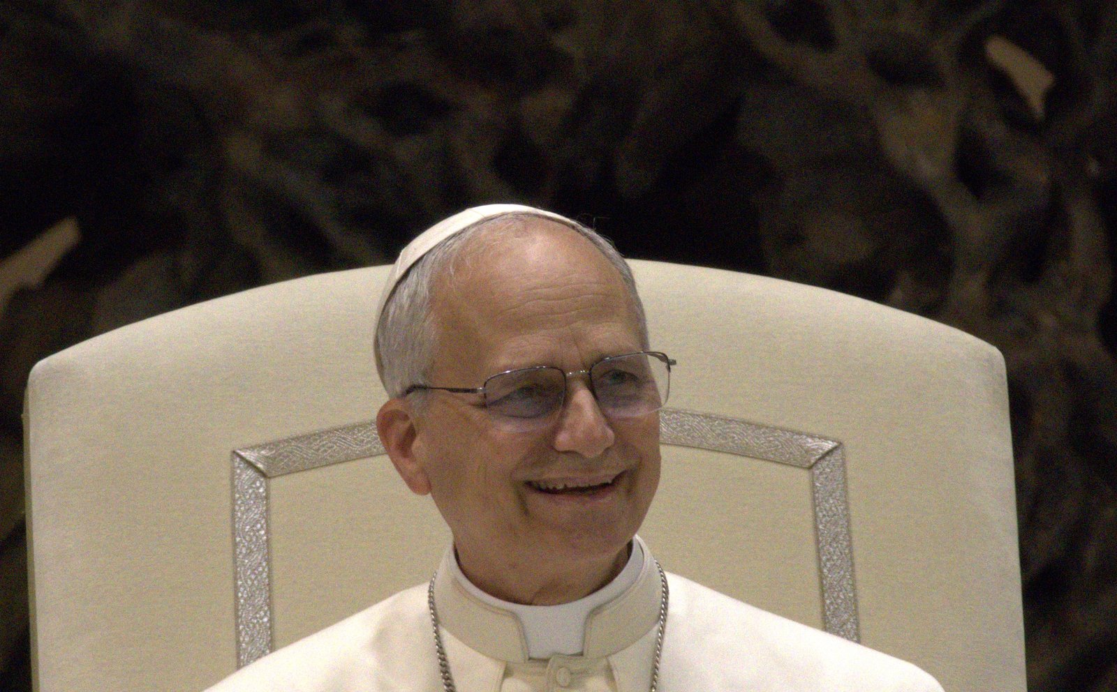 Papa Leão XIV sorrindo, sentado, em audiência no Vaticano