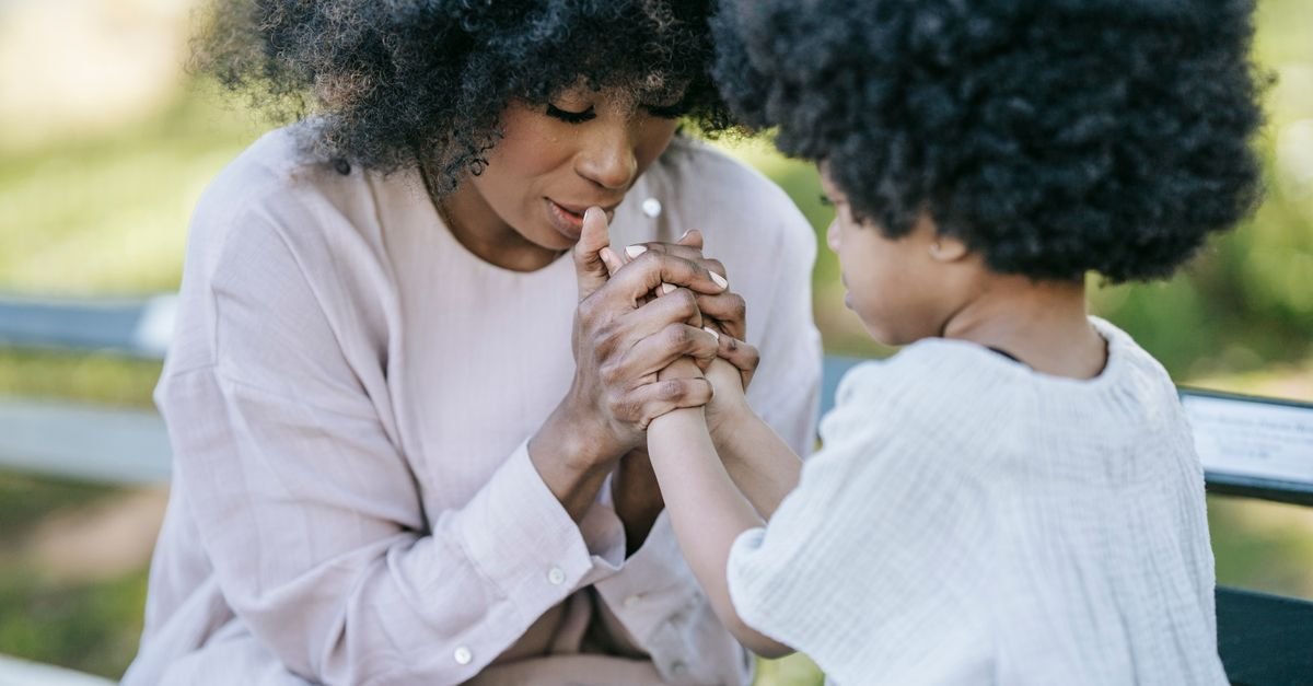 Mãe e filha de mãos dadas em momento de carinho ao ar livre