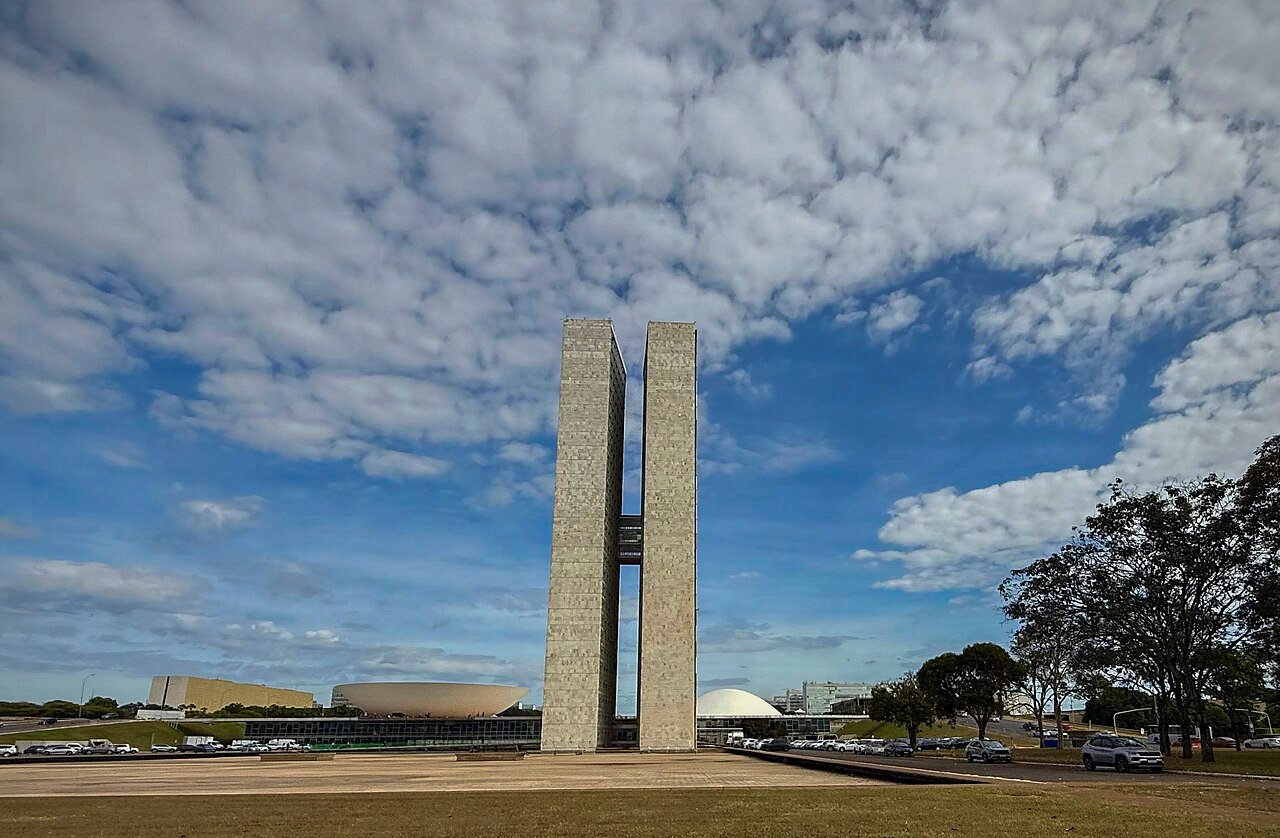 Torres do Congresso Nacional e cúpulas, em Brasília, sob céu parcialmente nublado