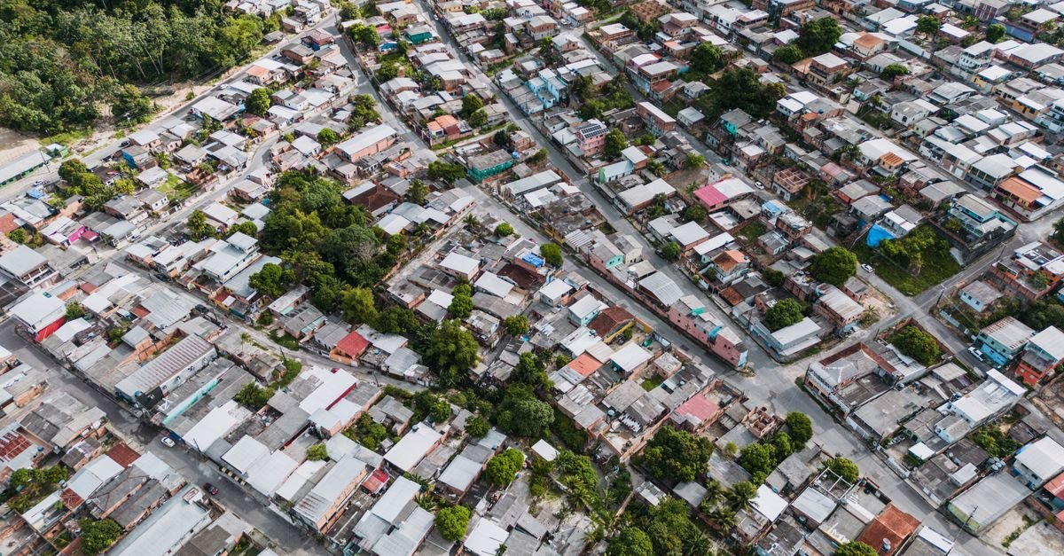 Vista aérea de bairro residencial com casas de telhados variados e ruas arborizadas