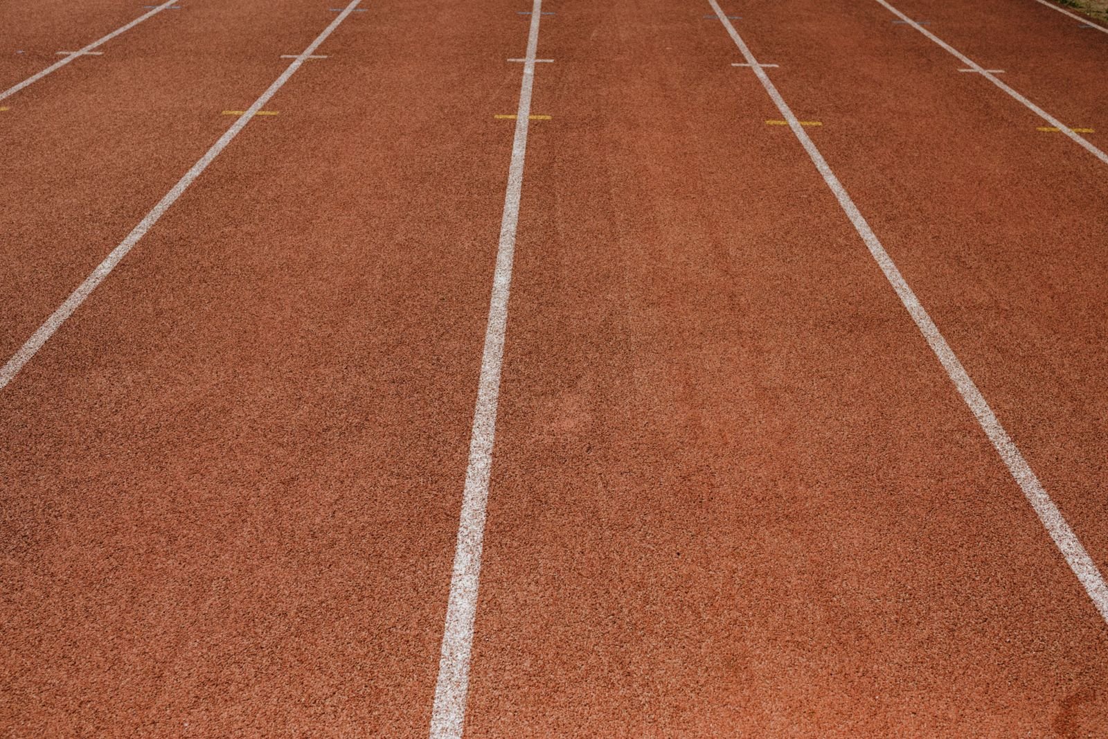 Pista de atletismo vazia com raias demarcadas por linhas brancas, imagem ilustrativa do teste de aptidão física