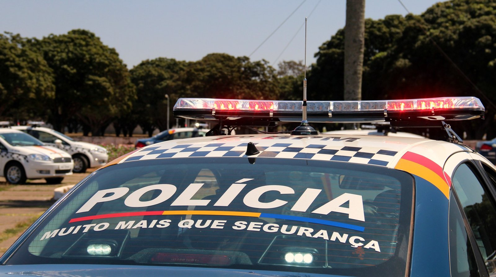 Parte traseira de uma viatura da PMDF com o giroflex aceso e a inscrição Polícia