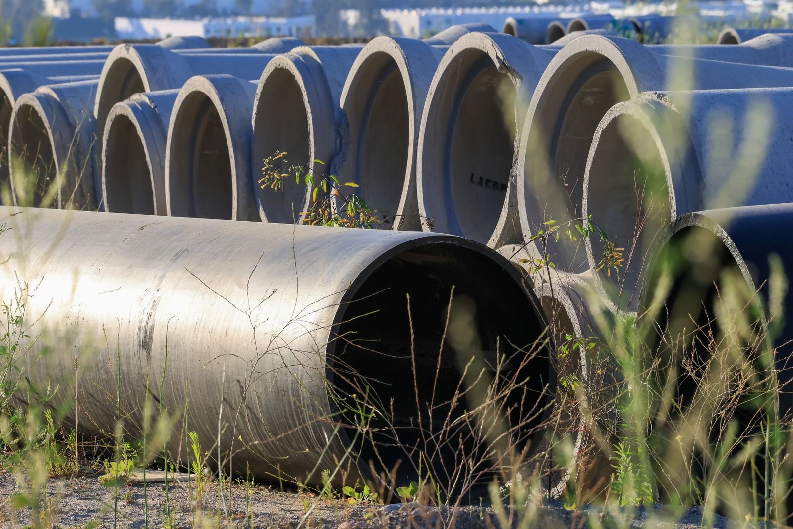 Tubos de concreto empilhados em canteiro de obras, foto de arquivo
