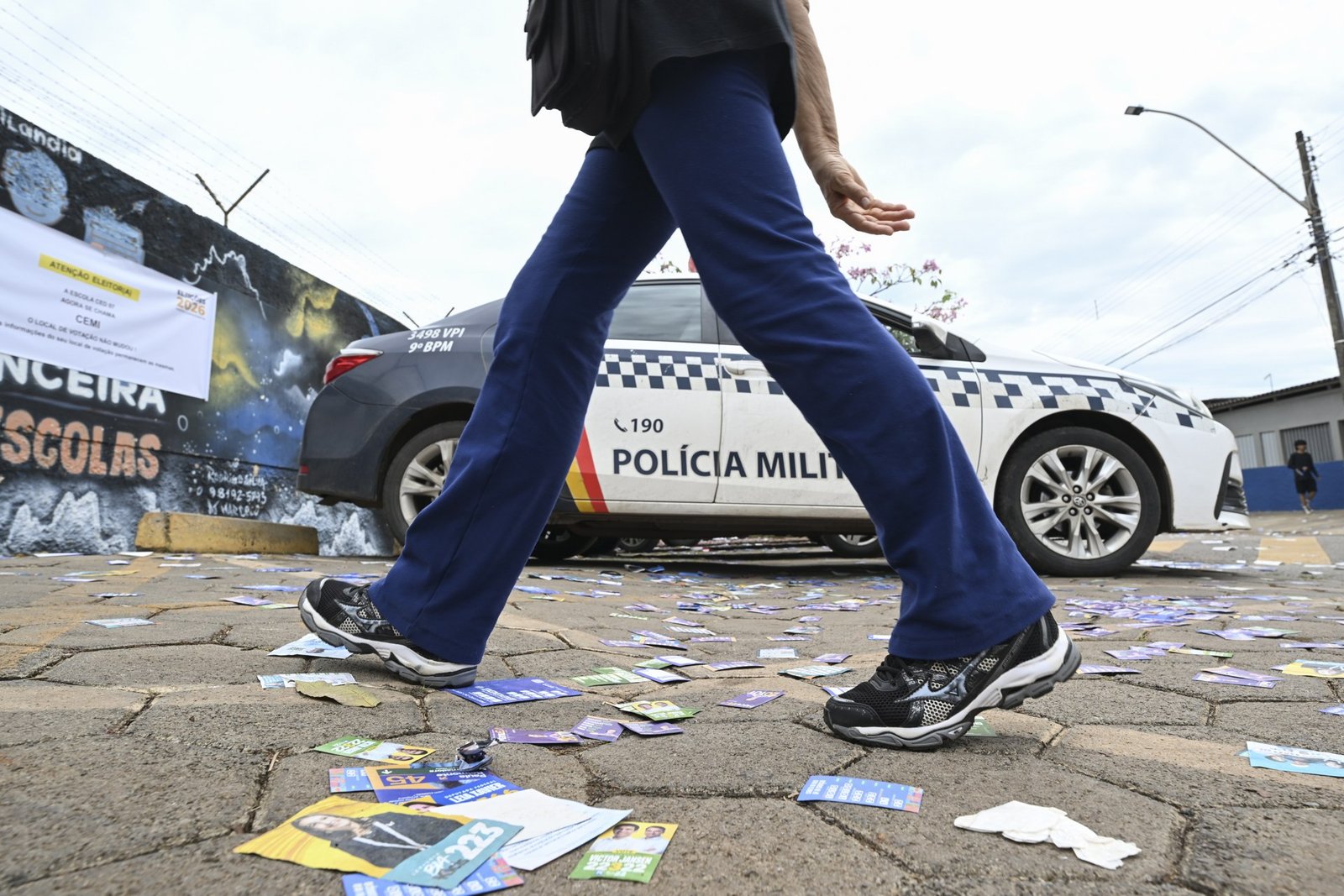 Viatura da Polícia Militar do DF estacionada ao lado de santinhos espalhados no chão perto de um local de votação, no primeiro turno de 2026