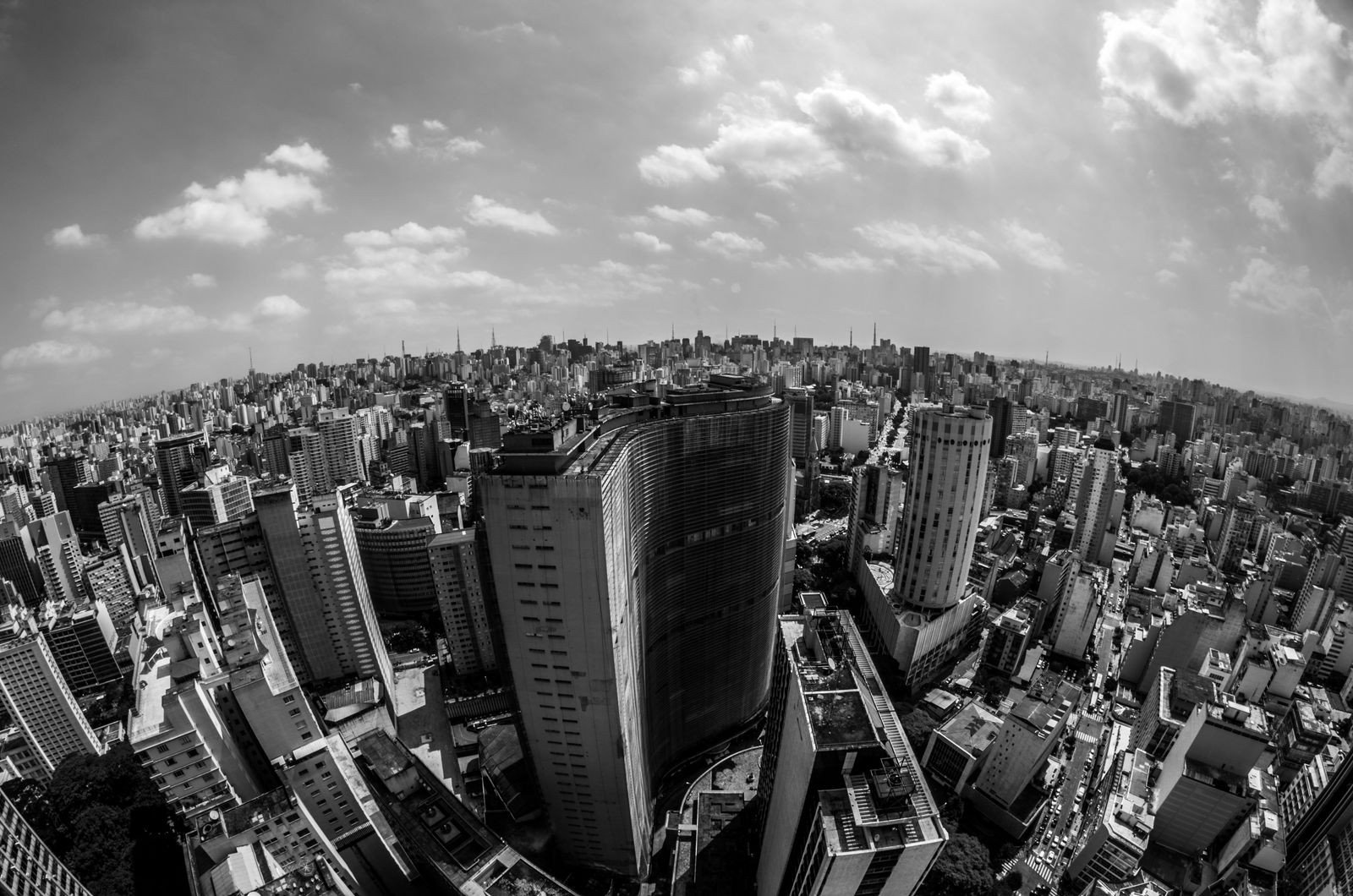 Vista aérea em preto e branco do centro de São Paulo, com o Edifício Copan em primeiro plano e a cidade até o horizonte