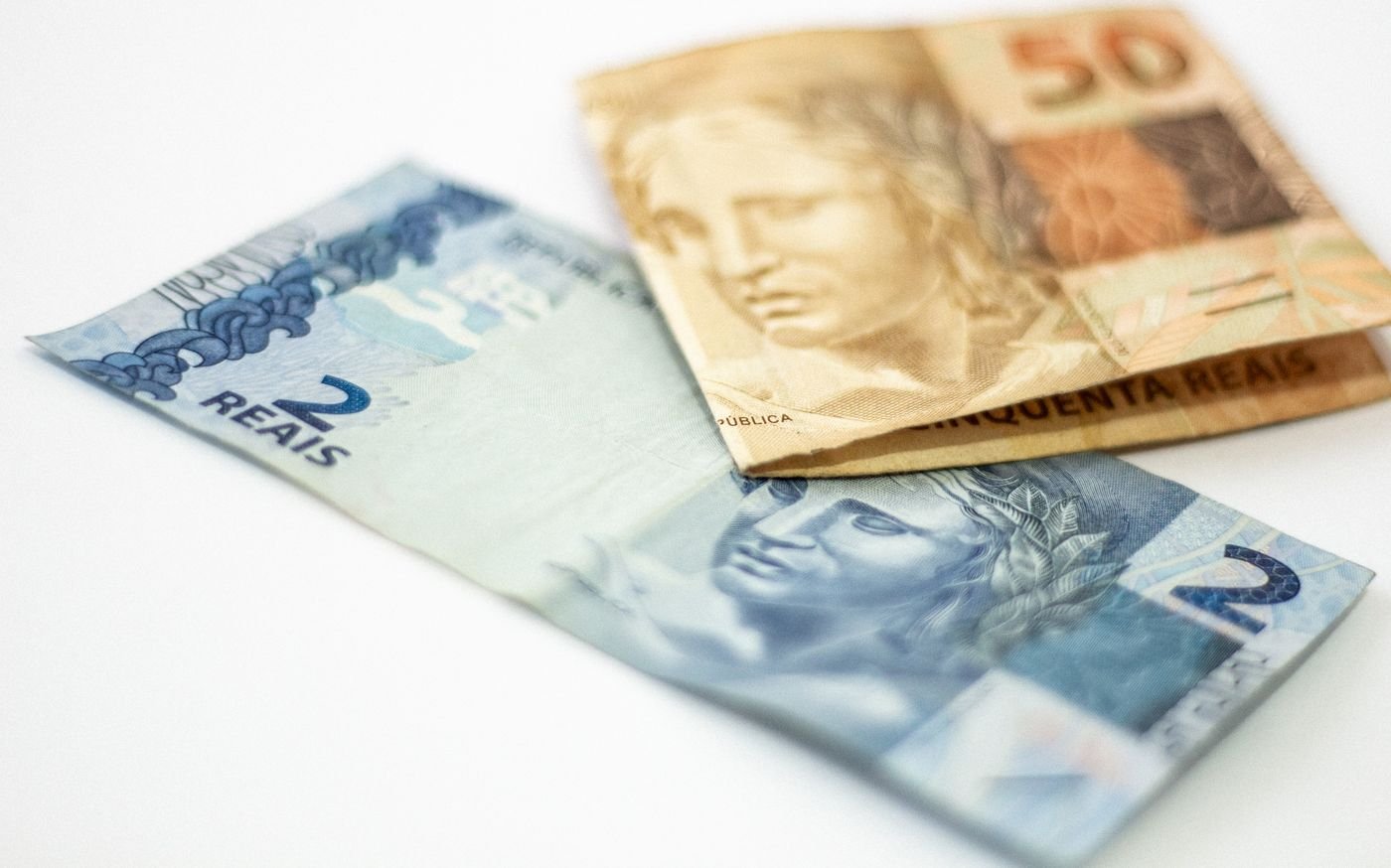Cédulas de dois e cinquenta reais sobre fundo branco
