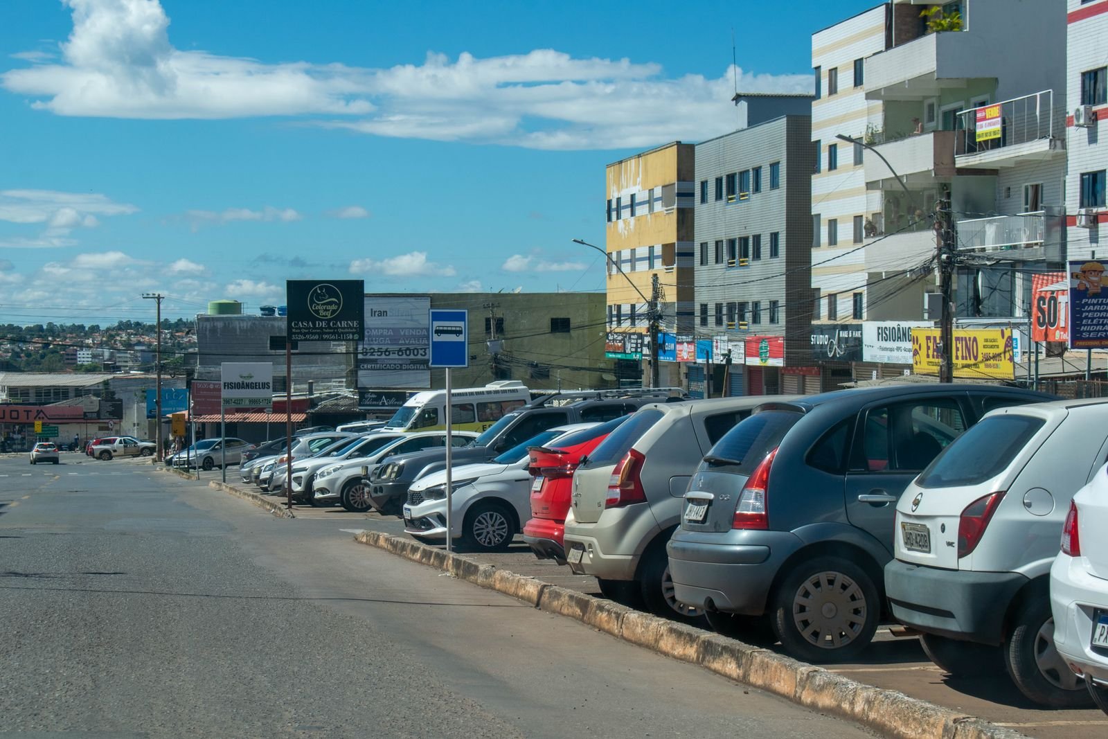 Rua comercial com carros estacionados e lojas em uma região administrativa do Distrito Federal (foto de arquivo)
