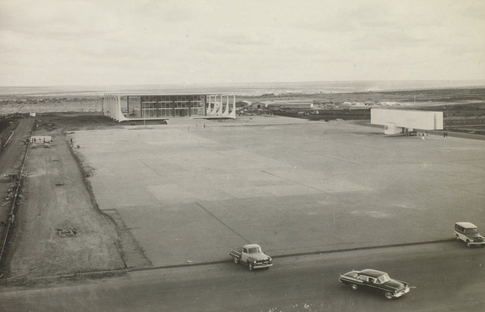 Foto histórica em preto e branco do prédio do Supremo Tribunal Federal na Praça dos Três Poderes, em Brasília, ainda sem arborização, com carros antigos na pista