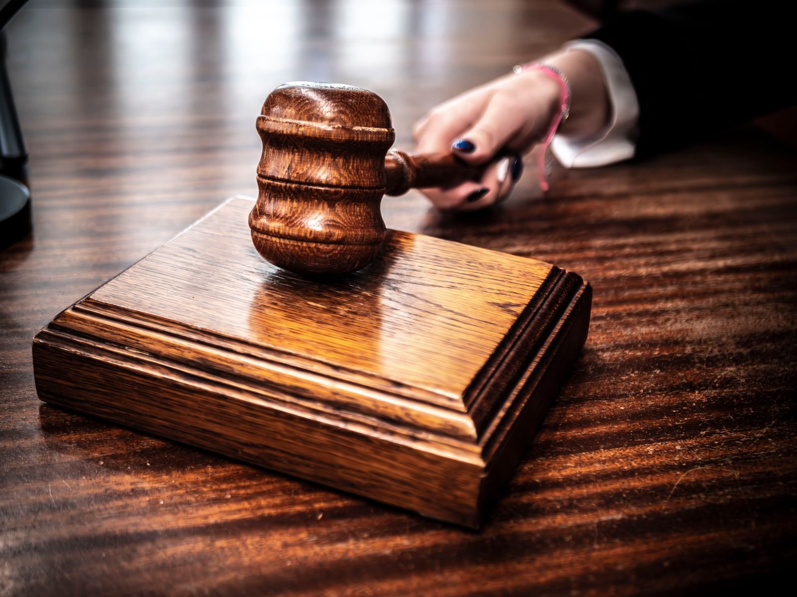 Martelo de madeira sobre base em uma mesa de tribunal; imagem ilustrativa