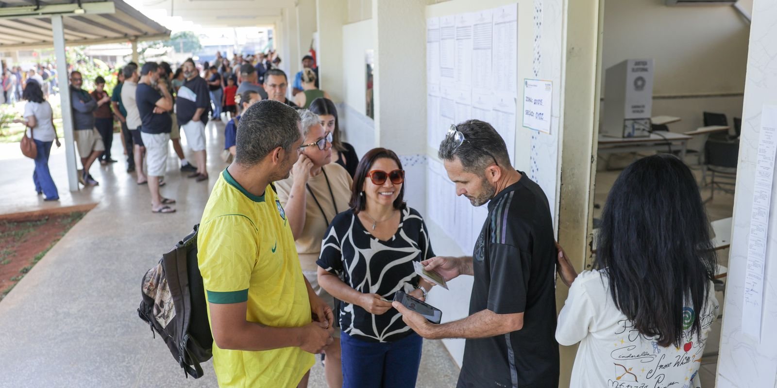 Eleitores em fila e conferindo a lista de seções numa escola de votação em Brasília