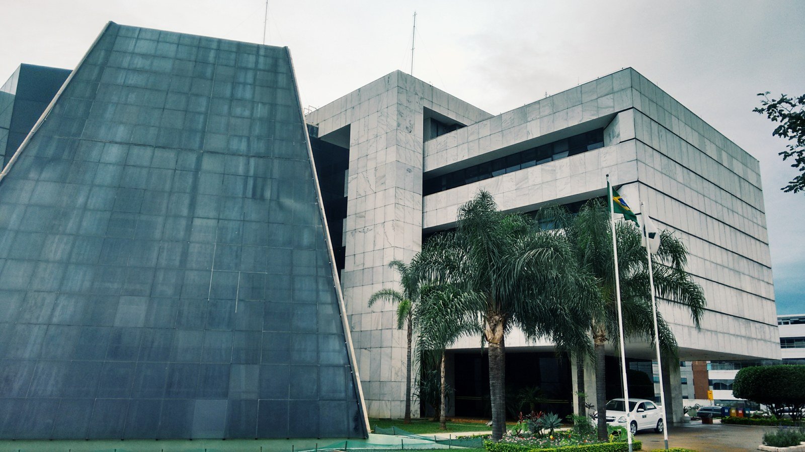 Fachada da sede do Tribunal Regional Eleitoral do Distrito Federal, em Brasília, com bandeiras e palmeiras na entrada