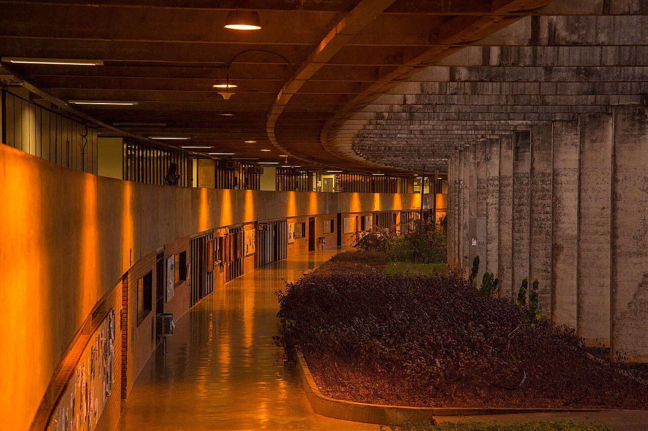 Corredor coberto com colunas de concreto e parede de painéis no campus Darcy Ribeiro da UnB